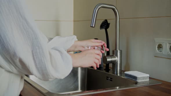 Woman Pouring Fresh Filtered Water Into Glass From Faucet Indoors