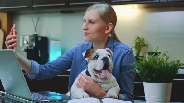 Caucasian Woman Making Selfie with a Small Dog While Sitting at the Computer