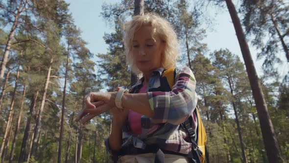 Senior Woman Using Smartwatch for Gps Navigation and Compass Trekking in Summer Forest