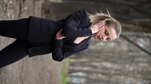 Young White Girl in a Black Jacket Talking on the Phone in a City Park