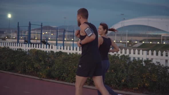 Woman with Her Boyfriend Are Jogging in Park in Evening, Talking Cheerfully