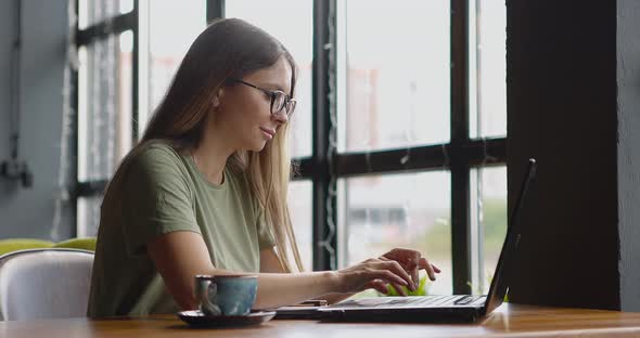 Woman Working Online and Drinking Coffee in a Cafe