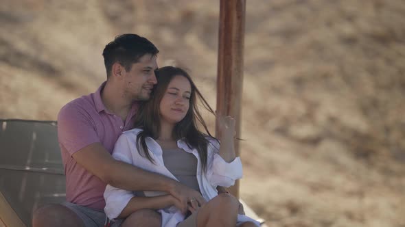 a Woman in a White Shirt with Long Hair and a Man in a Pink Tshirt Hugged and Sit