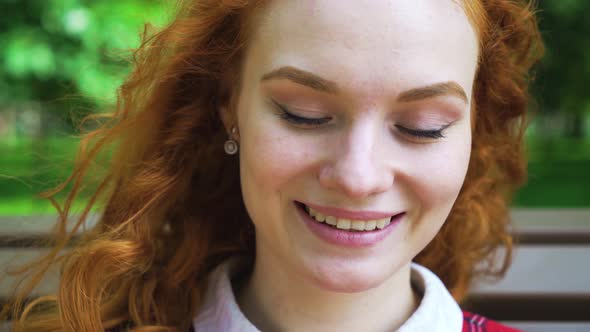 Happy Redhaired Girl Relaxing in Green Park on Sunny Day