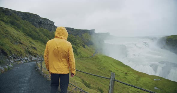 Male Tourist Wearing Yellow Raincoat at Gullfoss Waterfall on Iceland in Icelandic Nature