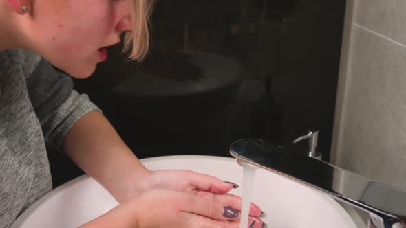 A Beautiful Woman Is Washing Her Face in the Bathroom at Home Beauty and Lifestyle Concept