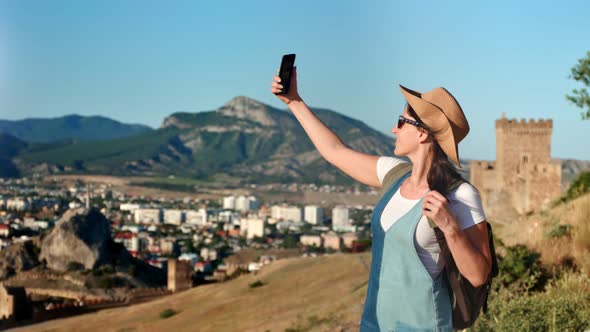 Active Backpacker Young Female Tourist Taking Selfie Using Smartphone Standing on Mountain