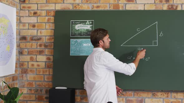 Portrait of caucasian male teacher teaching mathematics in the classroom at school