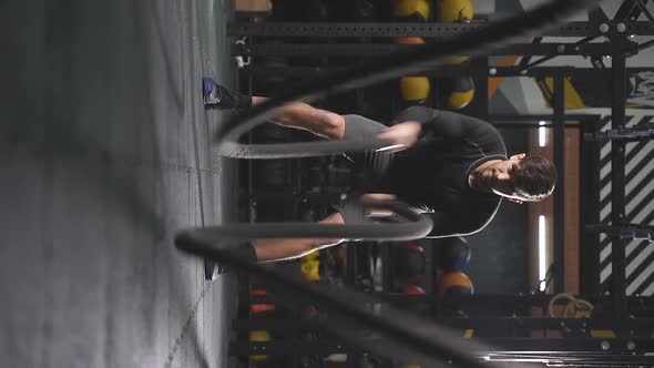 Strong Man in Sportive Shorts Doing Battle Ropes Exercise at Crossfit Gym