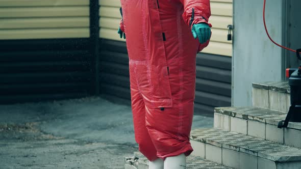 Medical Worker in a Red Suit Is Getting Disinfected with Chemicals