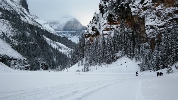 Tourists Trekking In The Banff National Park With Snow Capped Rocky Mountains And Forests. wide shot