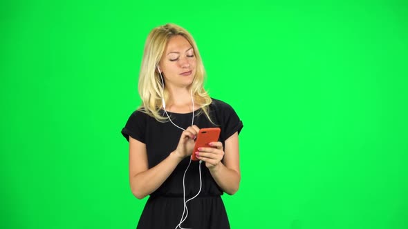 Cute Girl Goes in Headphones and Texting with Smartphone. Chroma Key. Slow Motion