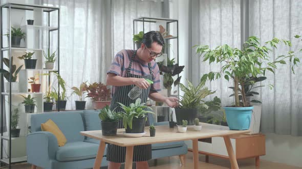 Asian Man Watering Plants At Home