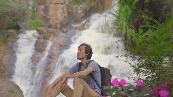 A Young Man Tourist Visits Waterfall in Mountains. Travel To Dalat Concept