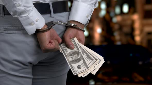 Close Up Handcuffed Man Holding Hundred Dollars.