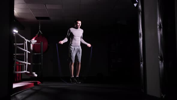 A Caucasian Athlete Trains on a Skipping Rope in the Middle of a Sports Hall with a Ring