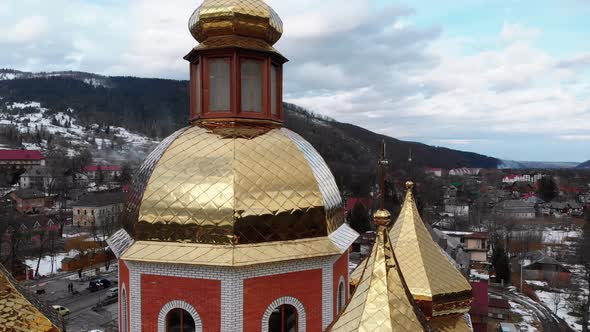 Aerial Drone View of Ukrainian Church with Golden Domes in Carpathian Village in Winter