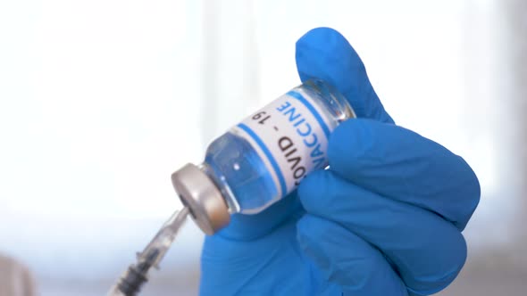 Doctor hands with blue surgical gloves holding syringe and COVID-19 vaccine. COVID-19 vaccine