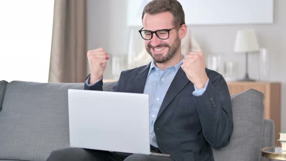 Young Businessman Celebrating Success on Laptop at Home 