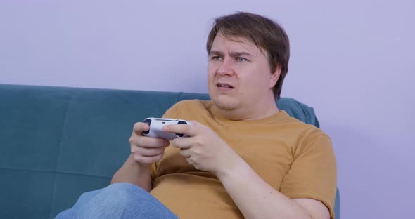 Young Man Enthusiastically Plays Video Game on Console Using Controller