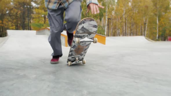 Skater Practicing in the Autumn Concrete Skate Park Making Tricks and Rides in Ramp