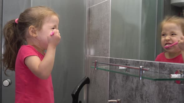 Little Girl Brushing Her Own Teeth in the Bathroom