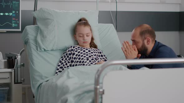 In Hospital Ward Little Child Patient Sleeping While Worried Father Praying for Disease Recovery