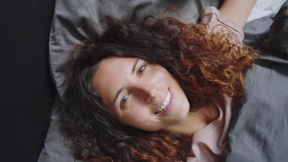 Joyous Woman Lying on Bed and Smiling at Camera