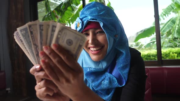 Arab woman is throwing dollars banknote from hand