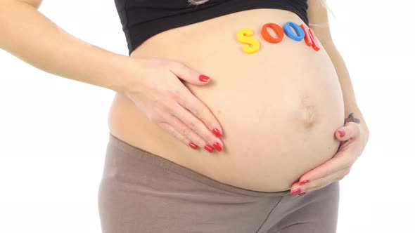 Cropped Image of Pregnant Woman with Coming Soon Sign on Her Belly Standing, White, Closeup