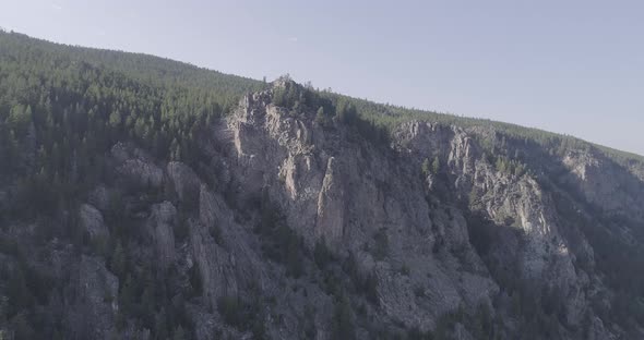 Aerial of steep mountains in a tree covered canyon. panning and sliding right to reveal bright sun w