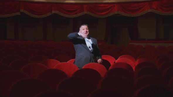 Man in empty theater. Rich man in suit taking off facial mask 