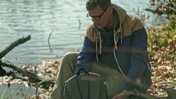 A Mature Man Tourist Traveler with a Backpack Walks in the Autumn Forest Near the River