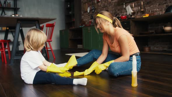 Mother and Son in Yellow Rubber Gloves and Casual Clothes are Smiling and Talking Washing Floor By