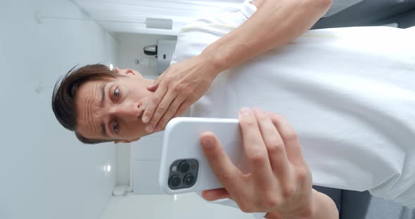 Vertical Video of Shocked Young Man Using Smartphone Loses Dissatisfied with Bad News at Home