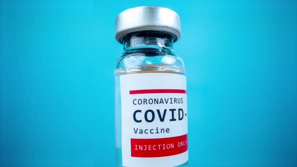 Glass Vial of the Covid19 Vaccine Against Blue Background