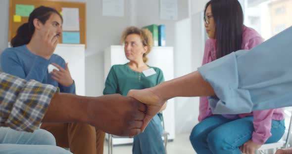 Close Up of African and Caucasian People Holding Hands Sitting in Circle During Therapy Session in