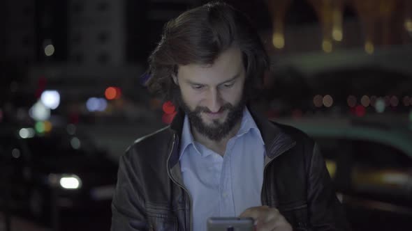 Happy Caucasian Man Using Smartphone in Night City