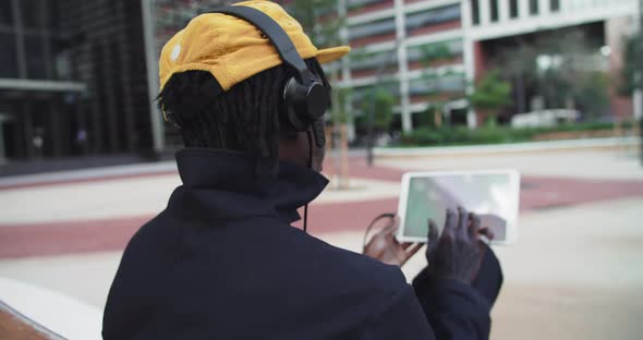 African American Man Works with Tablet Computer Urban Park Flips Through Feed on Social Networks