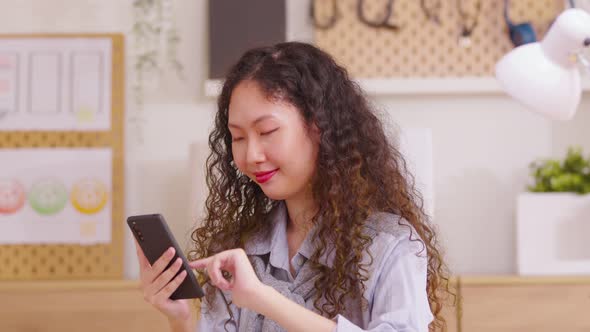 Happy long curly hair woman enjoy success on mobile phone at home office. Closeup joyful girl readin