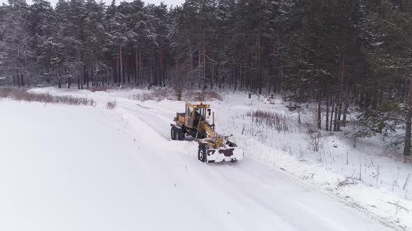 Aerial view of Snowblower Grader Clears Snow Covered Road next to the forest 12