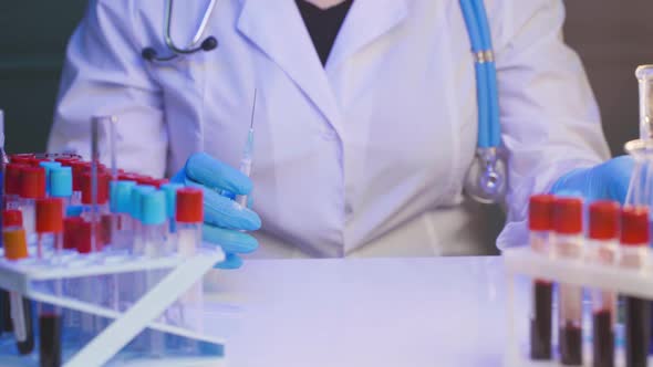 Female Doctor or Nurse Preparing Injection Syringe Filling with Ampoule Liquid in Clinic