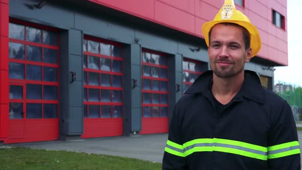 A Young Firefighter Puts on a Helmet and Smiles at the Camera with Hands Folded Across His Chest