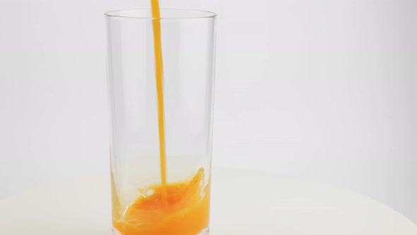 Pouring Orange Juice From Glass Jar Into Glass