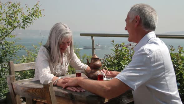 Couple drinking tea on terrace looking out over river Bosphorus Turkey Istanbul