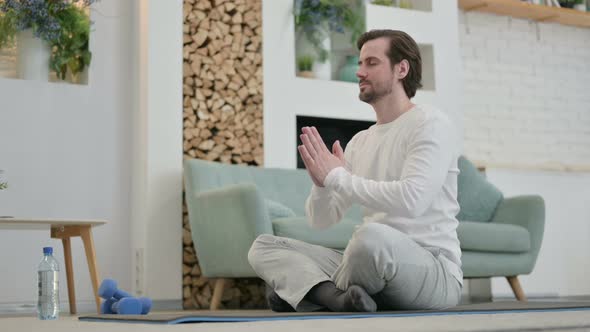 Young Man Meditating on Yoga Mat at Home