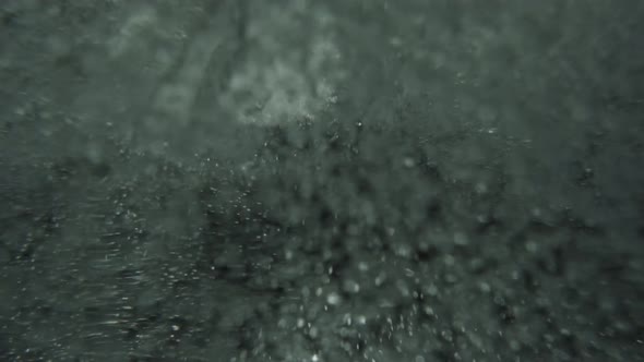 Super slow motion ice cubes falling into bubbly sparkling water black background