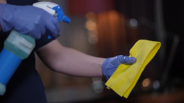Hands of Cleaner Spraying Sanitizer on Duster