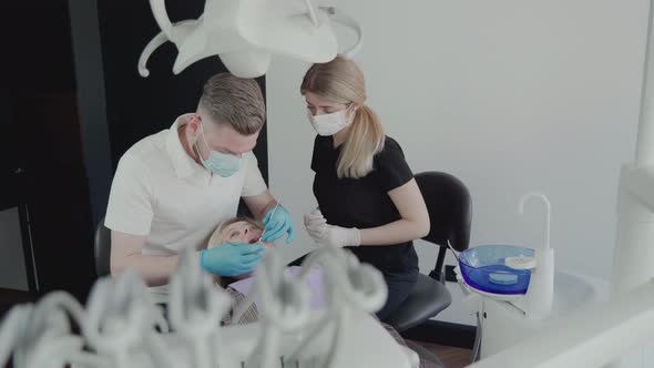 Two dentists, a man and a woman in protective masks and medical gloves