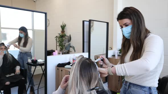 Hairdresser working on clients hair as they bleach it